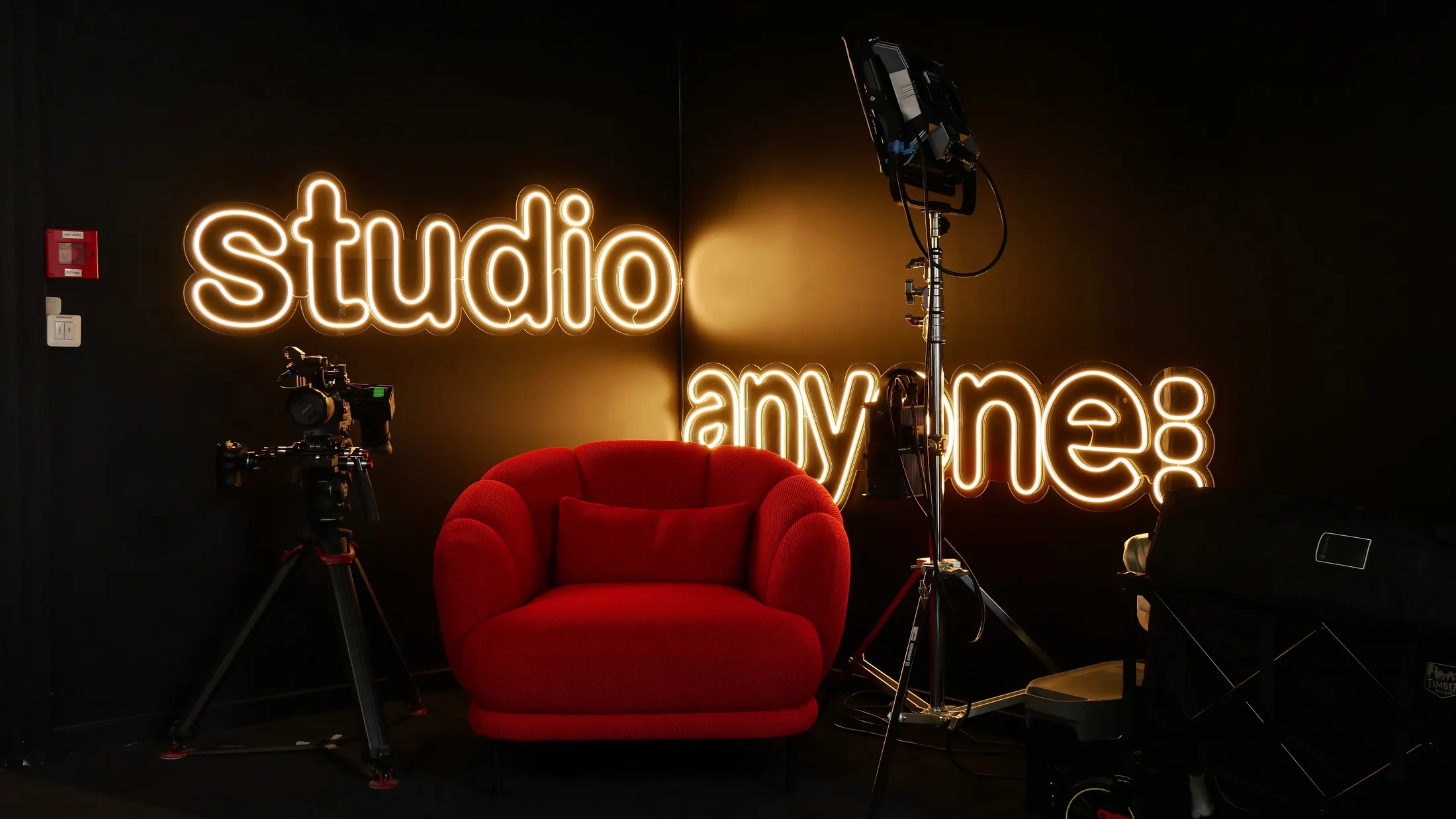 Le studio Anyone : néon « studio anyone », fauteuil rouge, caméra sur pied